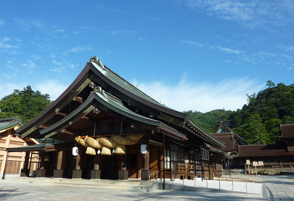 御本殿と拝殿の拡大写真。出雲大社は、現存する日本最古の歴史書である「古事記」と「日本書紀」に記されている日本最古の神社の一つです。神話によると、おおくにぬしのおおかみがお住みになる場所として、神々によって出雲大社は造られたと言われています。現在の大社造りの社殿は18世紀に再建されました。